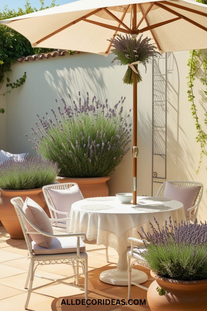 A bright and airy patio with a white dining table, pastel cushions, a large umbrella, and potted lavender plants.